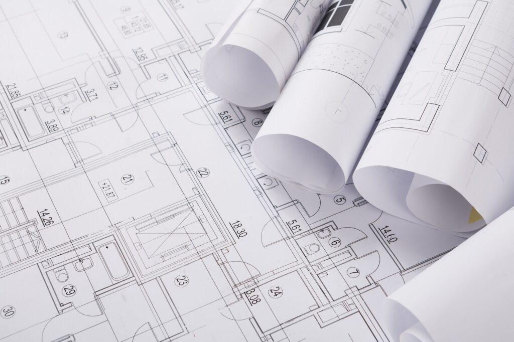 Rolled architectural drawings resting on a floor plan.