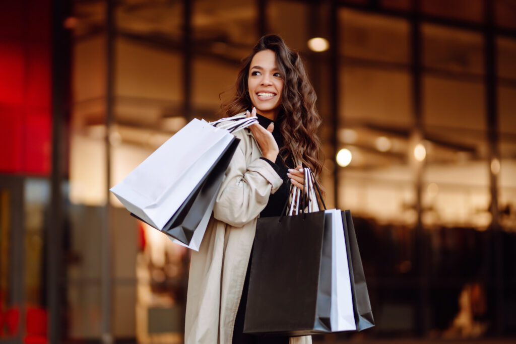 Young woman with shopping bags near mall. Spring Style. Consumerism, purchases, shopping, lifestyle.